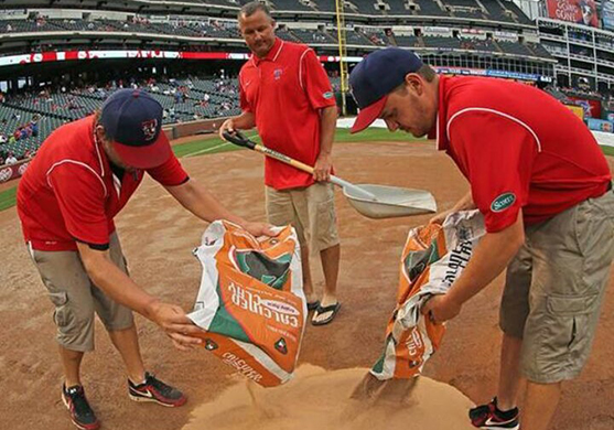 Auburn turfgrass management major Jared Nash, right, and co-workers disperse a drying agent on the field at Rangers Ballpark in Arlington following a heavy rain that fell a couple of hours before a Texas Rangers baseball game.